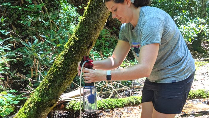 Woman using a water filtration system during a backpacking workshop in Red River Gorge.