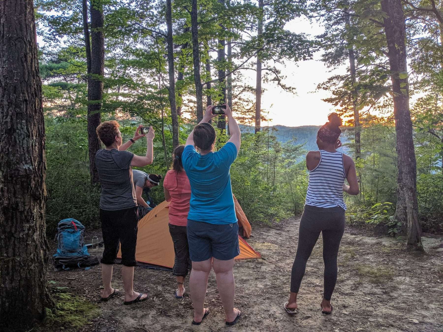 Women using phones to take pictures of the sunset while camping in Red River Gorge