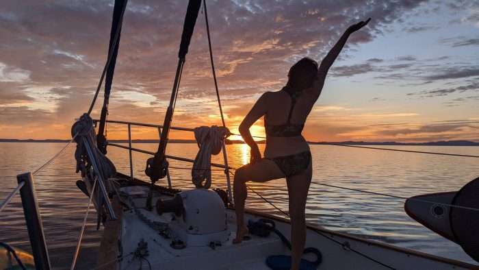 Woman in swimsuit standing on bow of small cruise ship watching the sunset in Baja Mexico