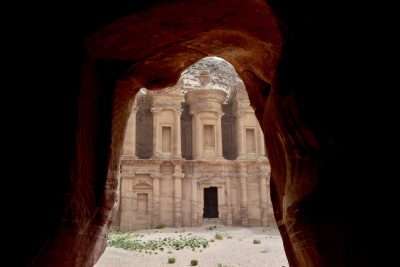A view of the stone-carved monestary Petra through a cave opening