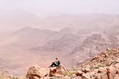 Explorer chick resting on a rock overlooking Jordan mountains