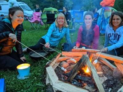 Group of women sitting around the fire with marshmallows