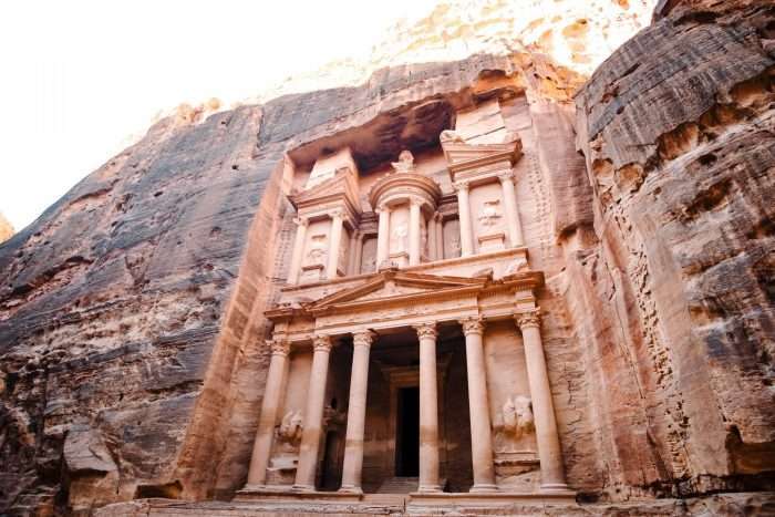 A building facade with columns carved into the side of a rock known as Petra