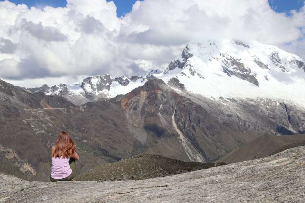 Woman sitting and looking out over a mountain range during a hike