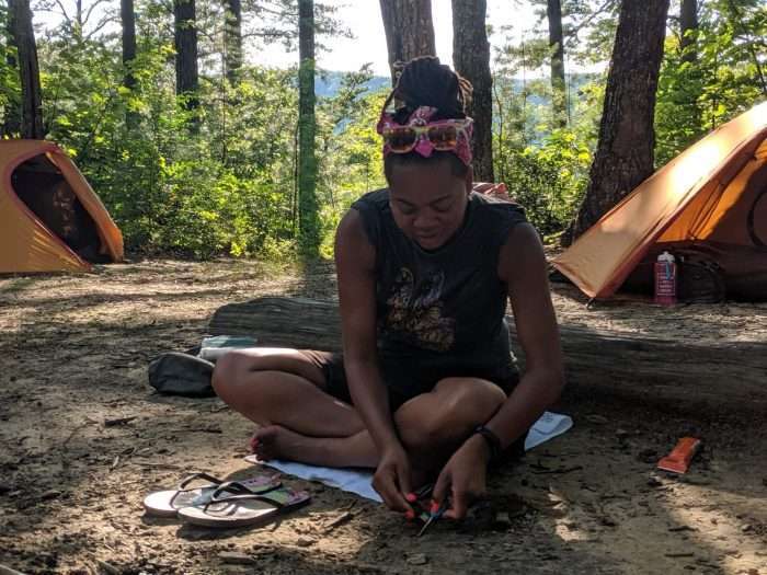 woman learning how to start a fire a camp while backpacking